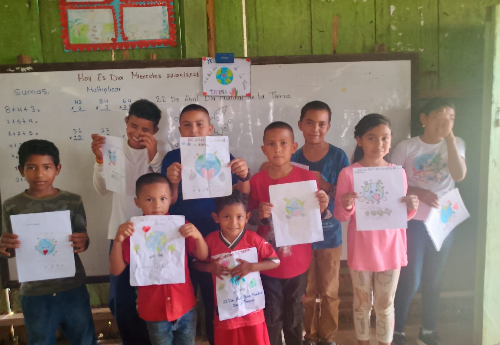 Children holding up their Earth Day drawings in a classroom