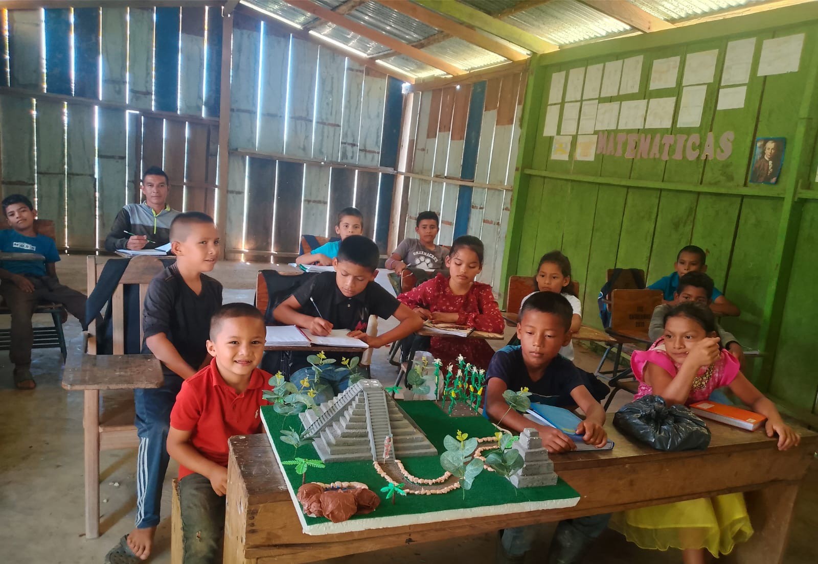 Children gathered around a table with a model of a pyramid in their classroom