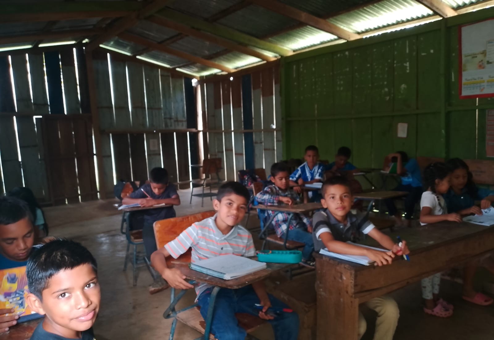 Children writing in notebooks at wooden desks in their classroom