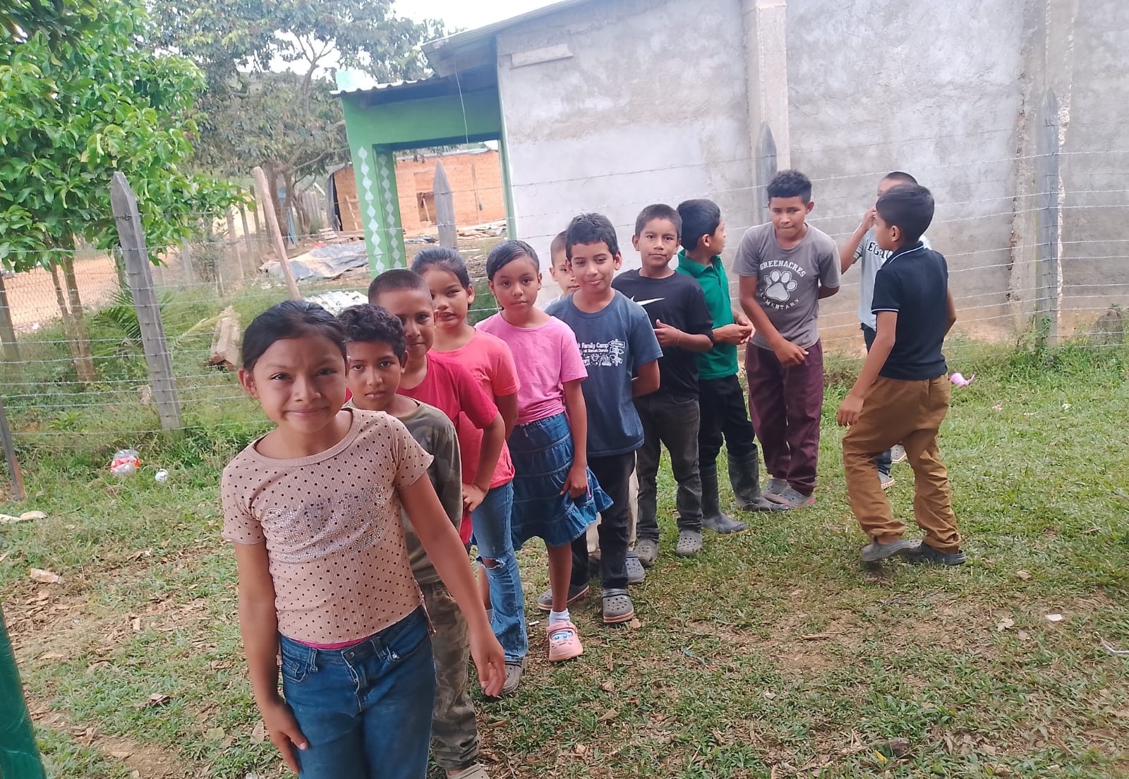 A group of children standing on the grass outside their school