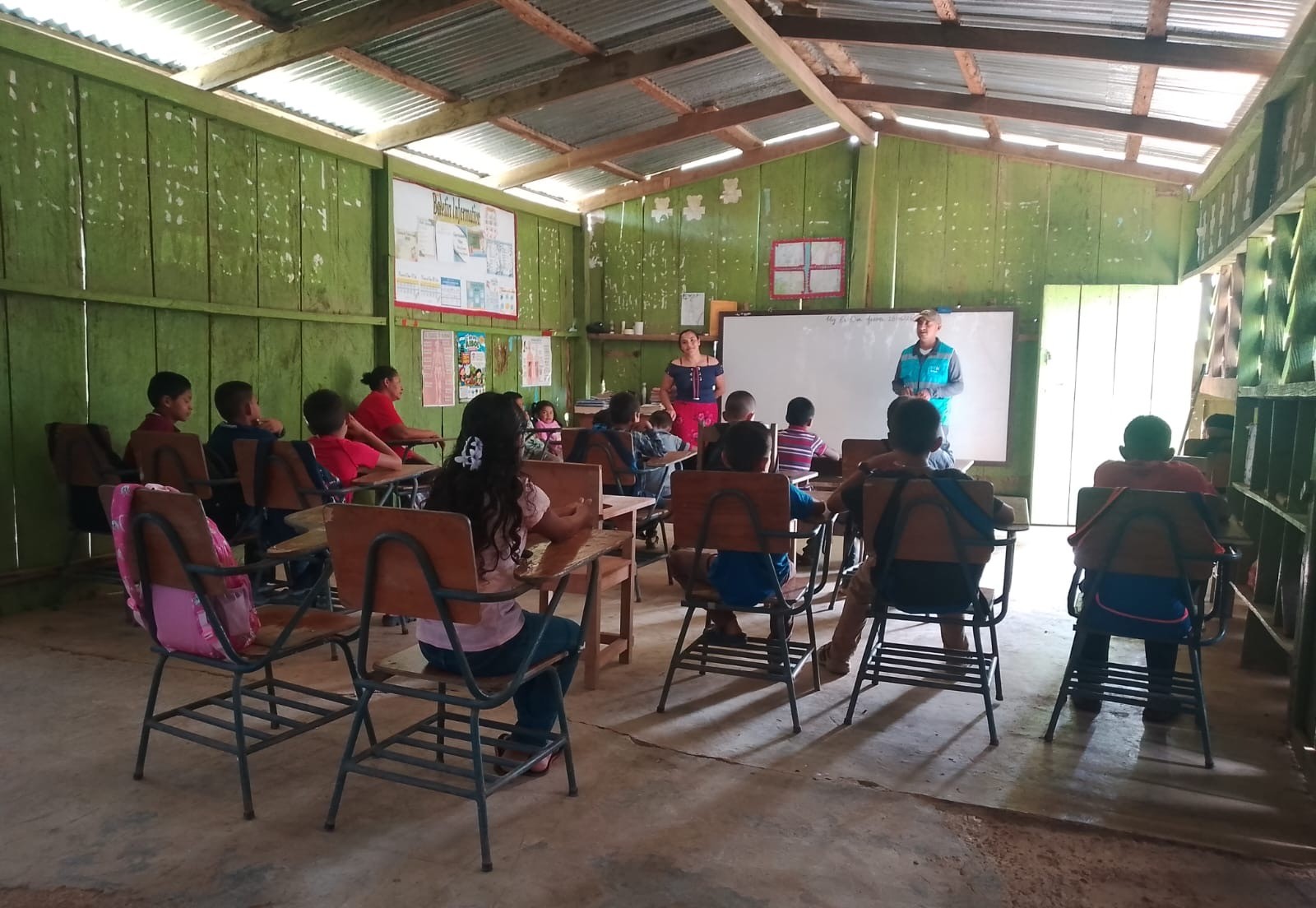 Children seated in a classroom listening to a lesson at the whiteboard