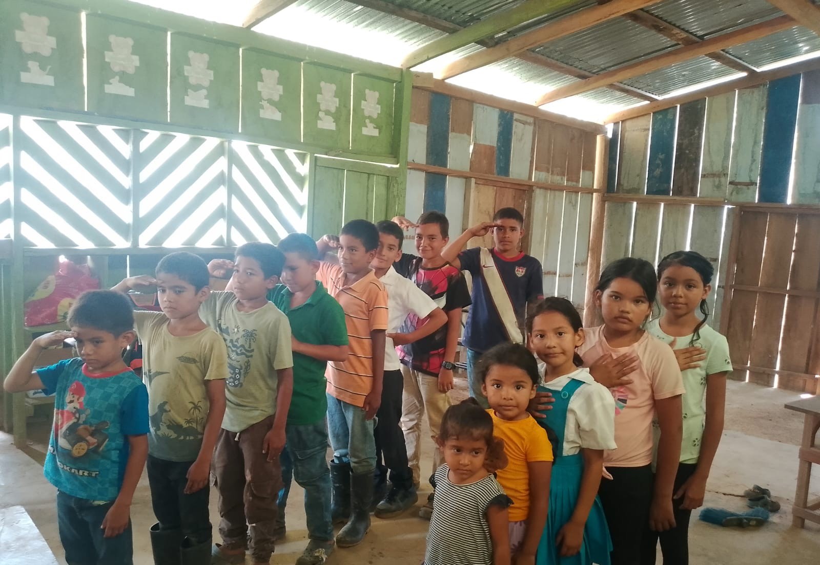Children standing in a line inside a room with a green patterned wall